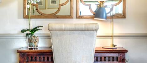 Un escritorio de madera con una silla, un espejo y una lámpara.