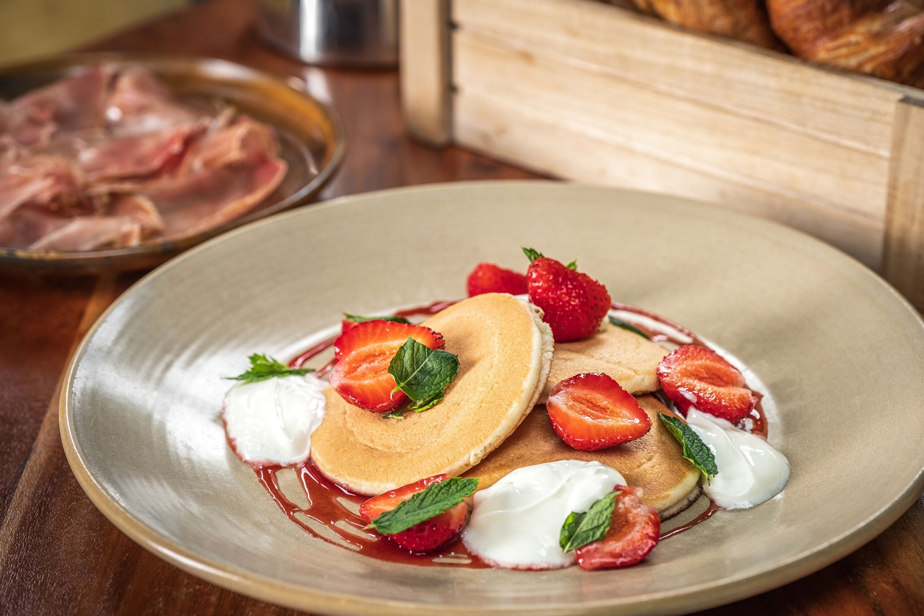 A plate of pancakes with strawberries and whipped cream.
