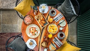 Una mesa redonda de madera con alimentos para el desayuno, como pan, huevos y zumo de naranja.