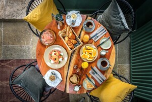 A round wooden table with breakfast items including bread, eggs, and orange juice.