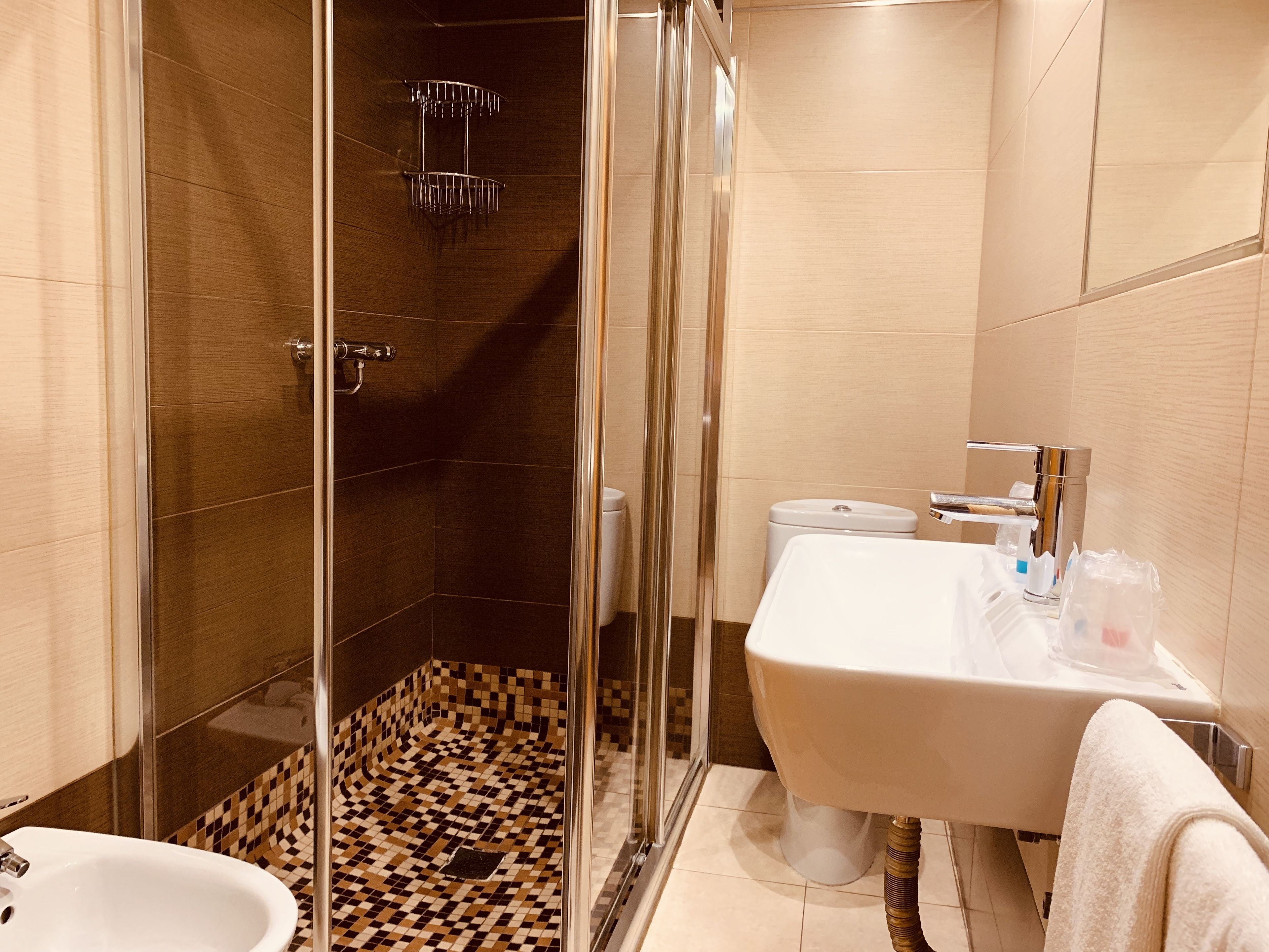 A modern bathroom with a shower, toilet, sink, and a tiled floor.