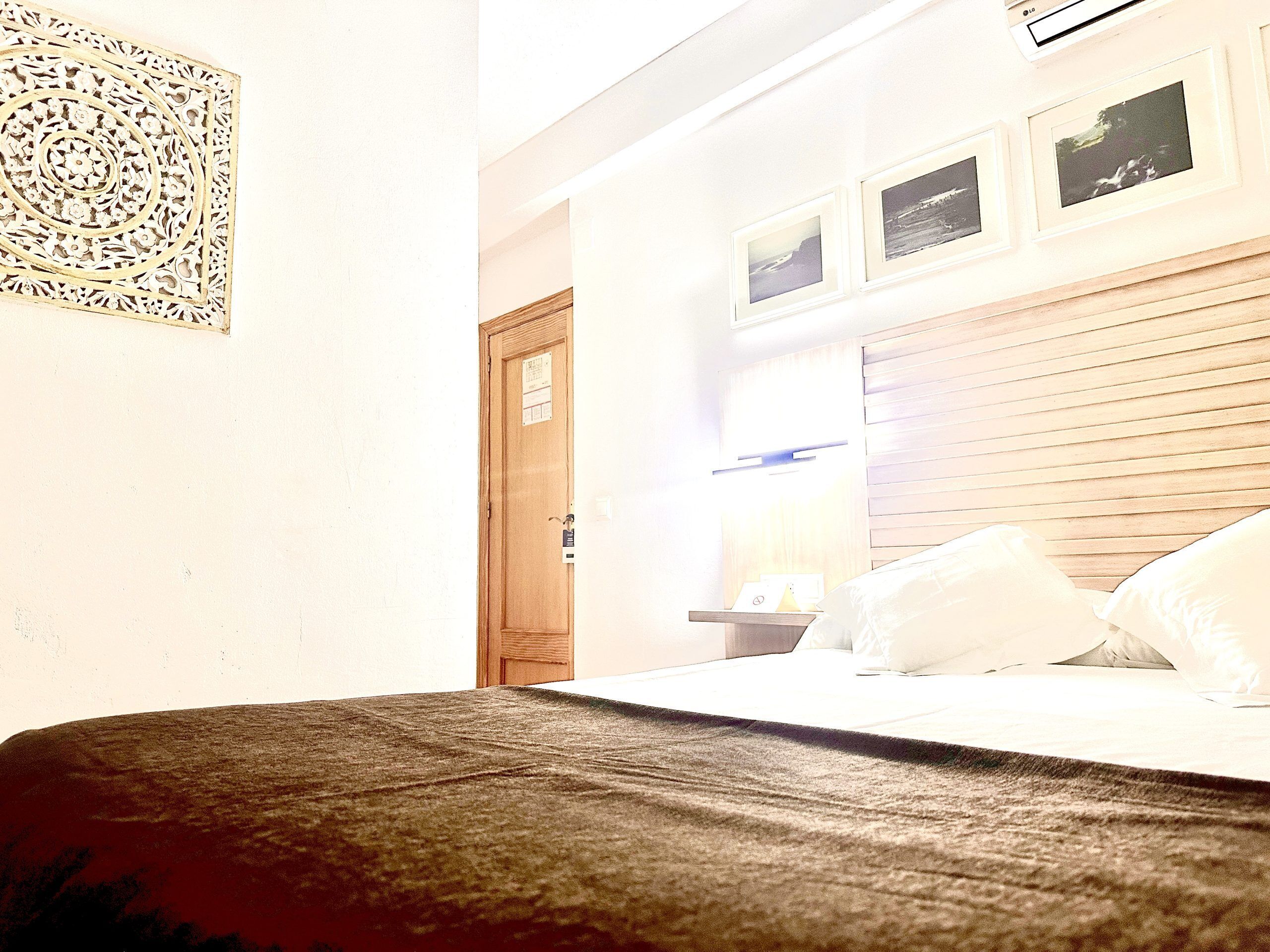 Een hotelkamer met een bed, een houten hoofdbord, een wandtelevisie en ingelijste foto's.