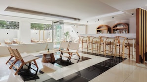 A modern bar area with a glass partition, wooden chairs, and a bar counter with shelves of bottles. - Lotus Rise Hotel (Hersonissos)