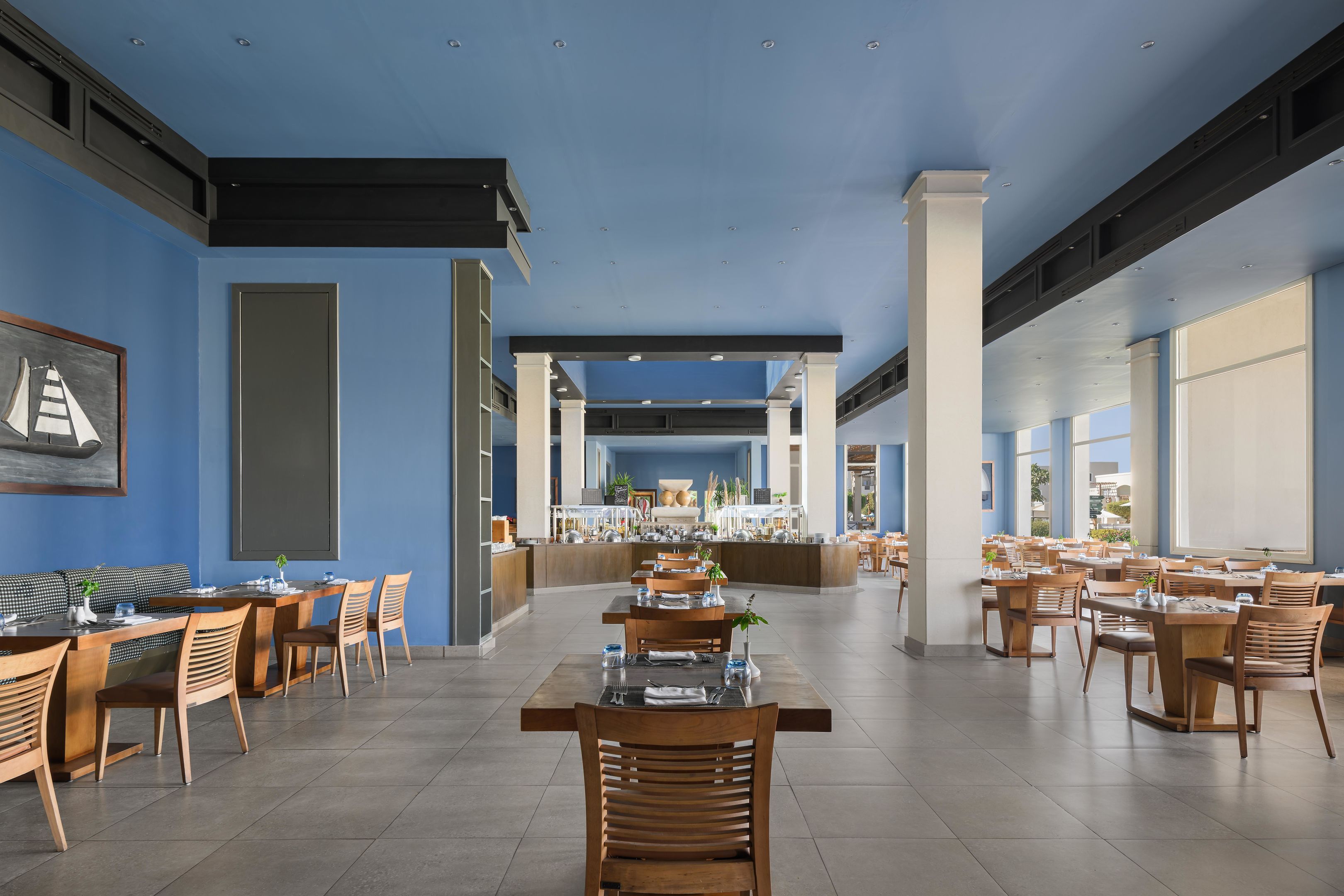 Un restaurante espacioso con techos altos, ventanas amplias y una zona de bar central.