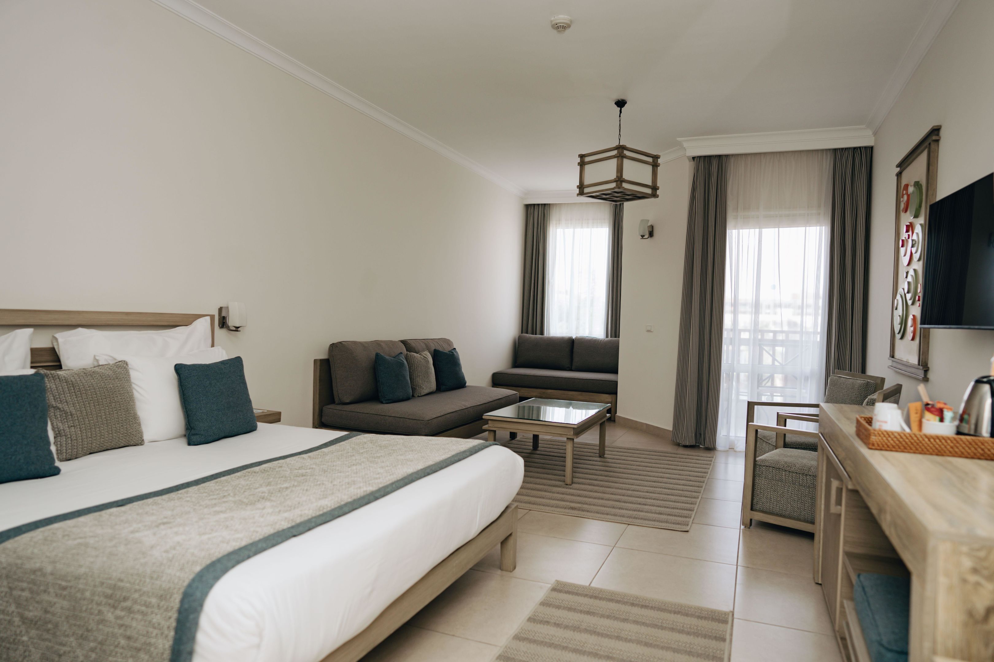Une chambre d’hôtel équipée d’un lit, d’un canapé, d’une table basse, d’une télévision et d’un bureau.