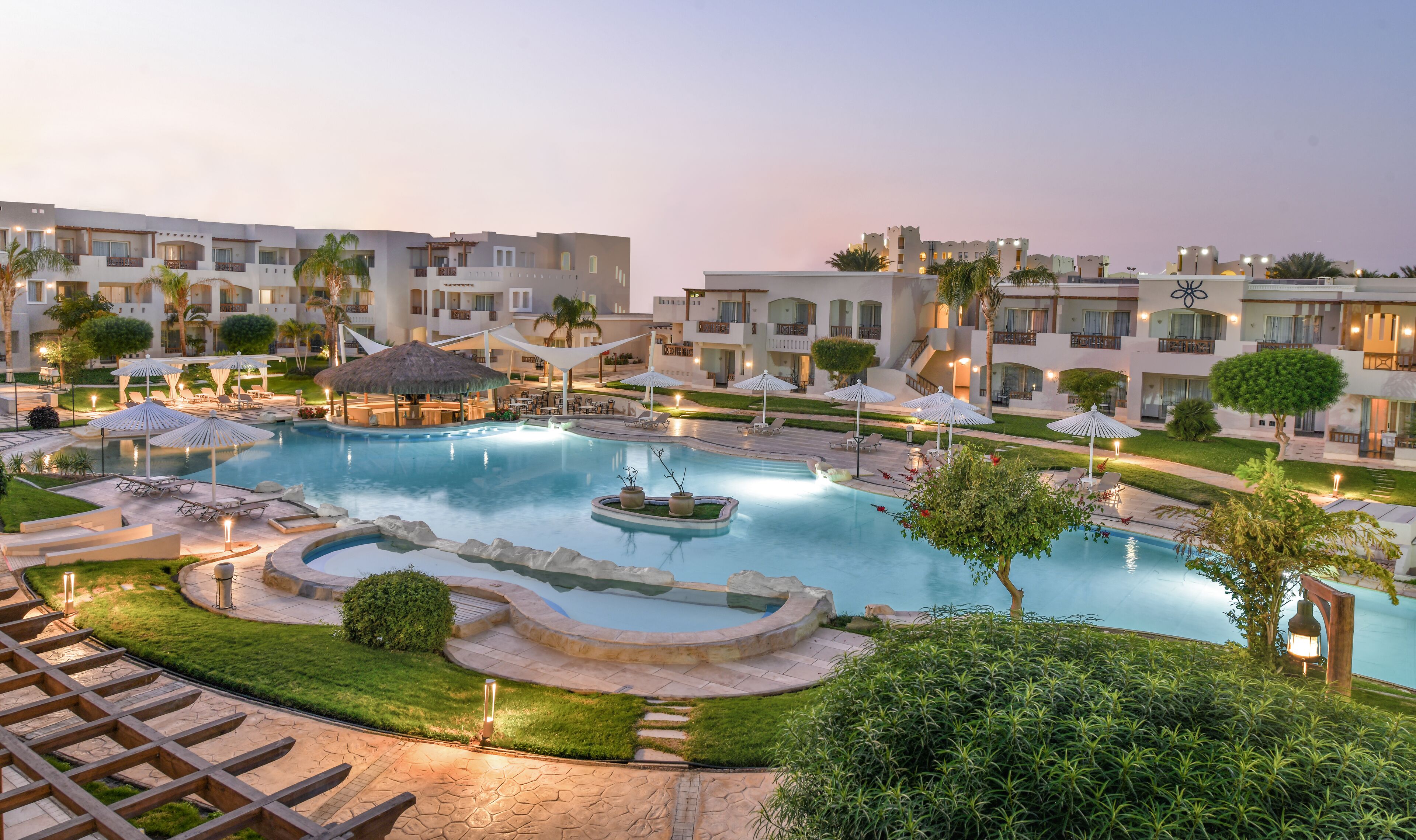 A resort with a large swimming pool, lounge areas, and multiple buildings with balconies.