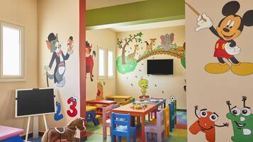 A children's playroom with cartoon character murals, colorful furniture, and educational toys.