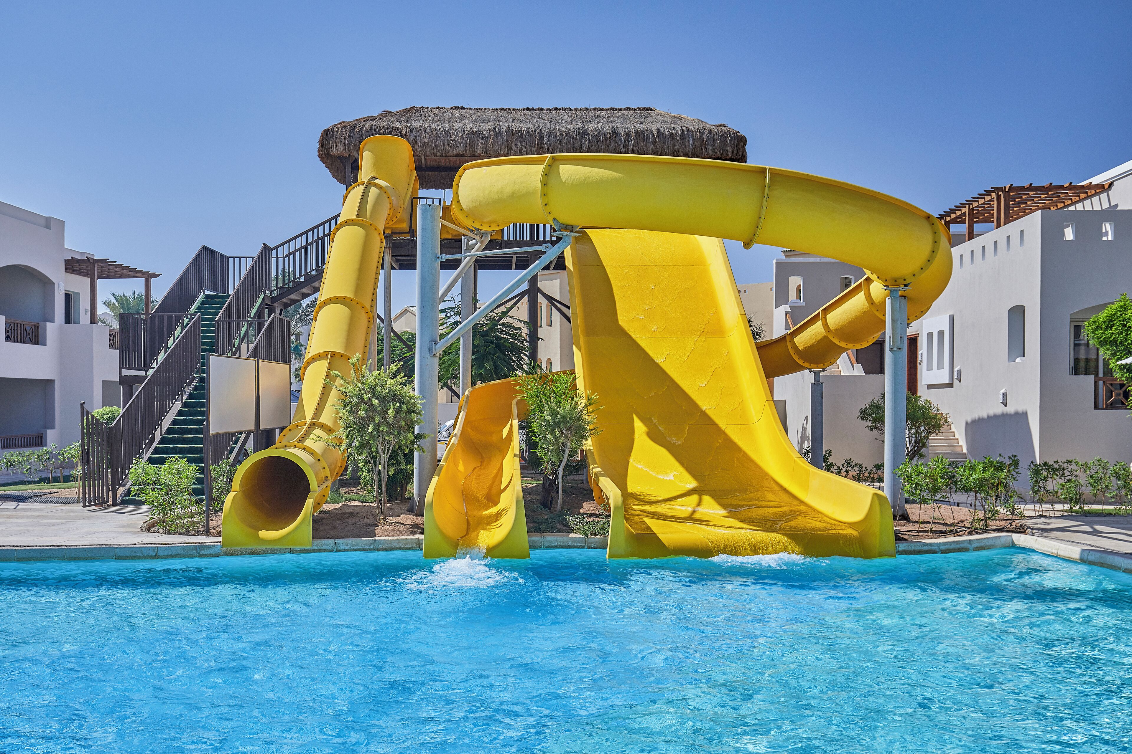 A pool with a large yellow water slide structure.