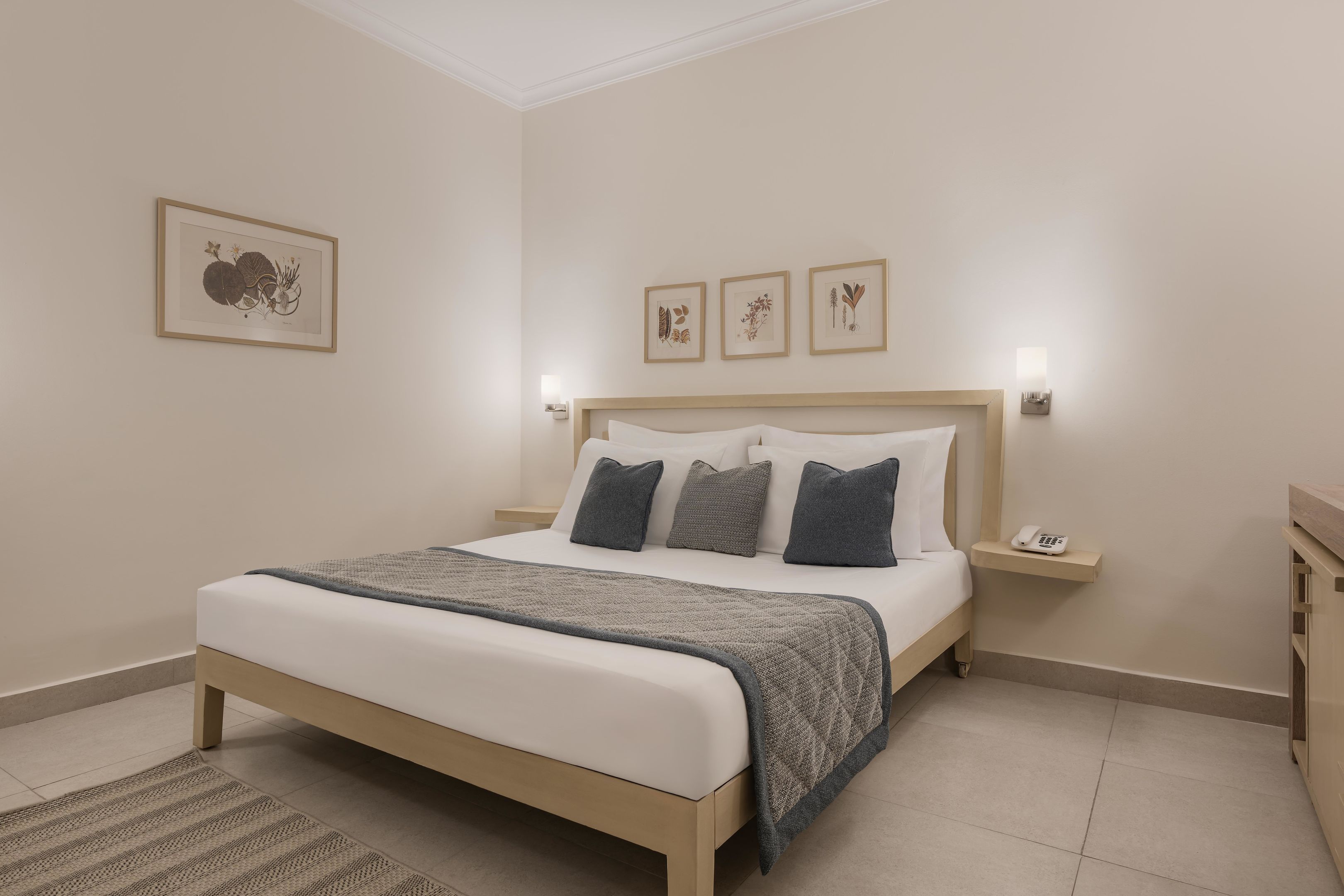 A neatly arranged bedroom with a bed, bedside tables, and wall-mounted light fixtures.