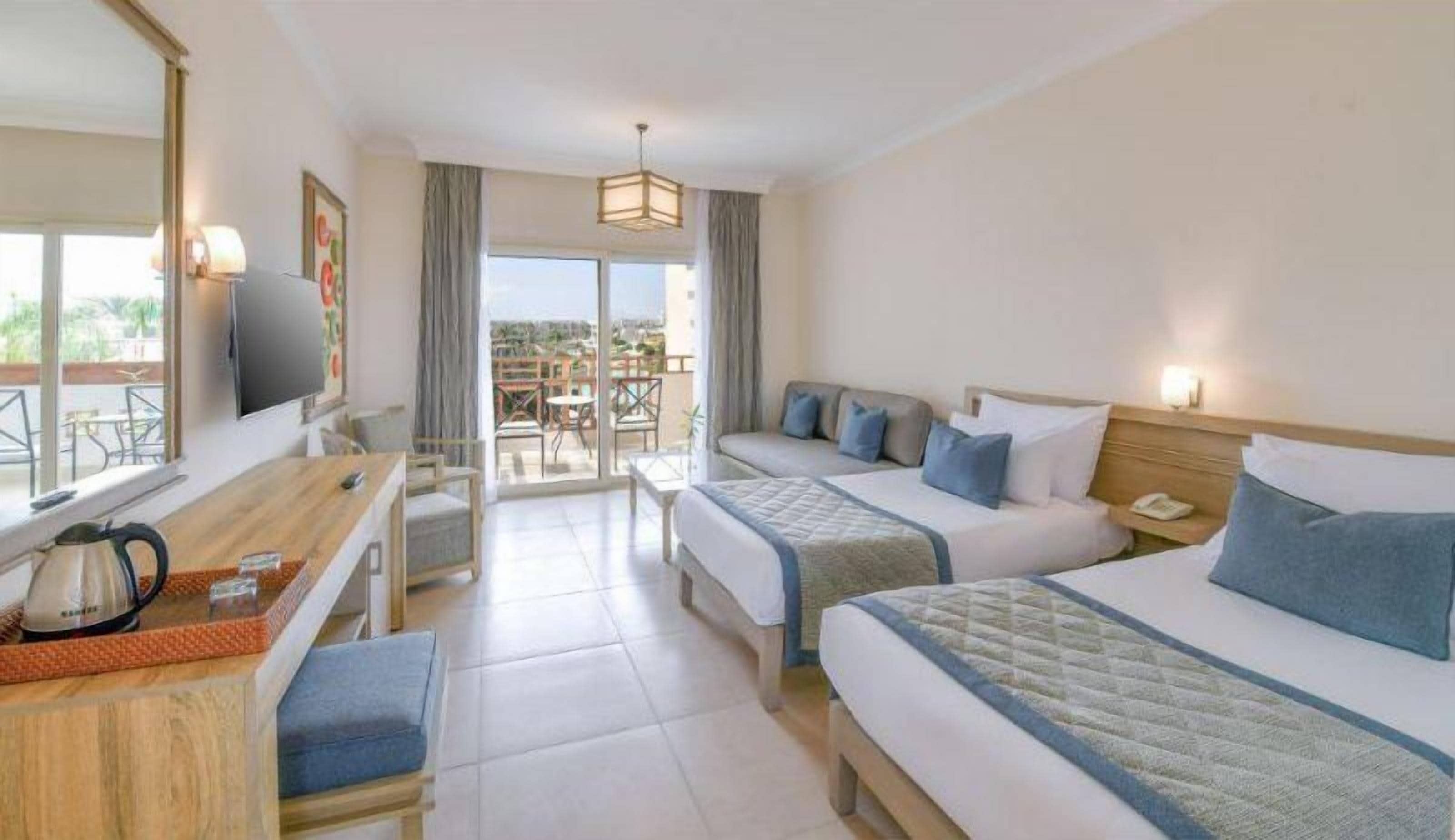 A hotel room with two beds, a desk, a chair, a television, and a balcony with a view.