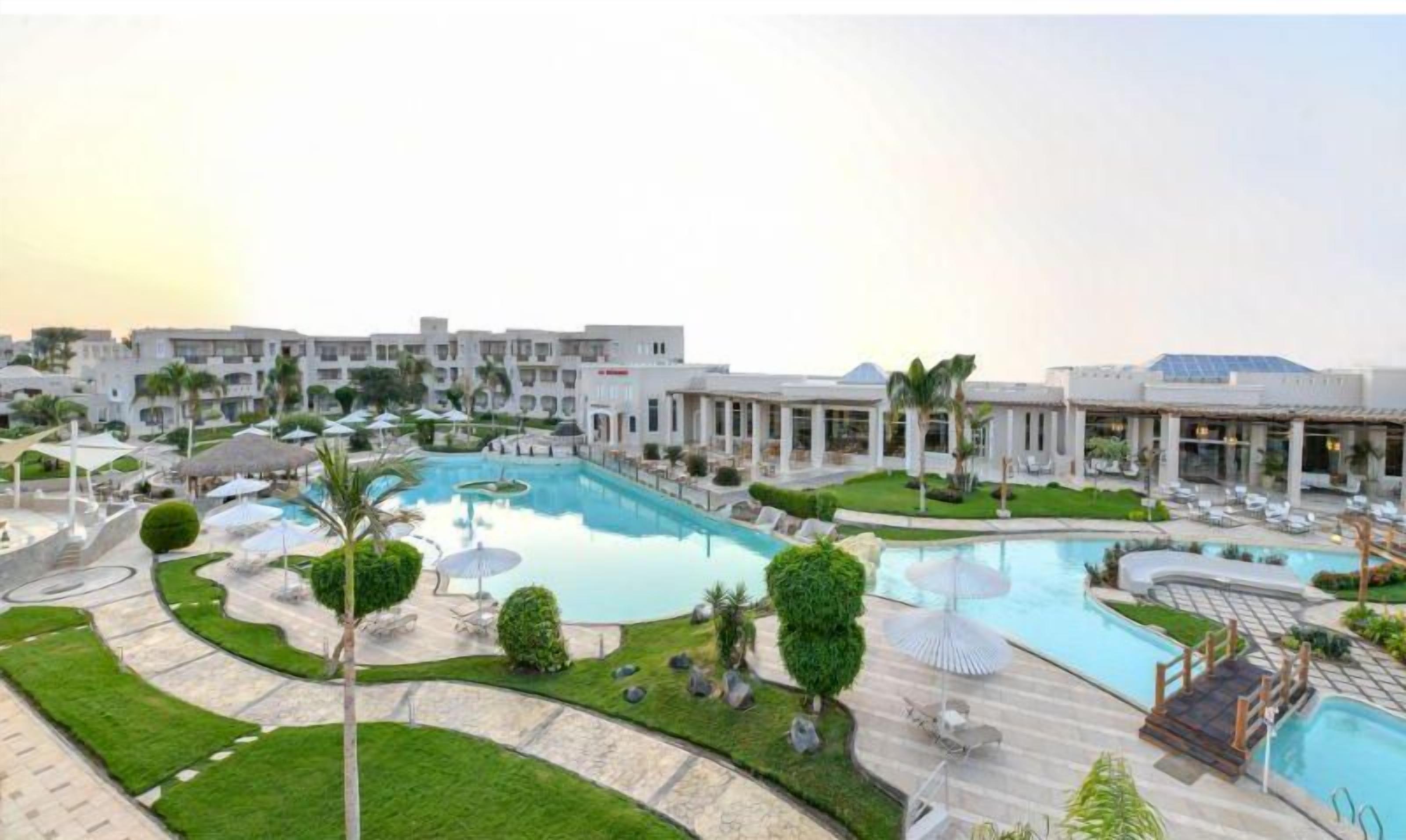 A resort with a large pool, lounge areas, and modern buildings.
