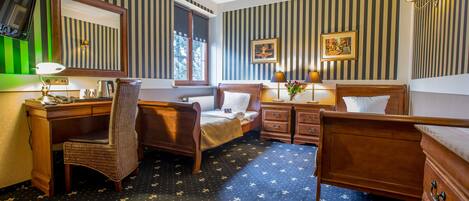 A hotel room with a large bed, a desk with a chair, a dresser, a mirror, and a window.
