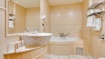 Un baño con un lavamanos grande, una bañera y un inodoro. Hay toallas y artículos de aseo en el mostrador.