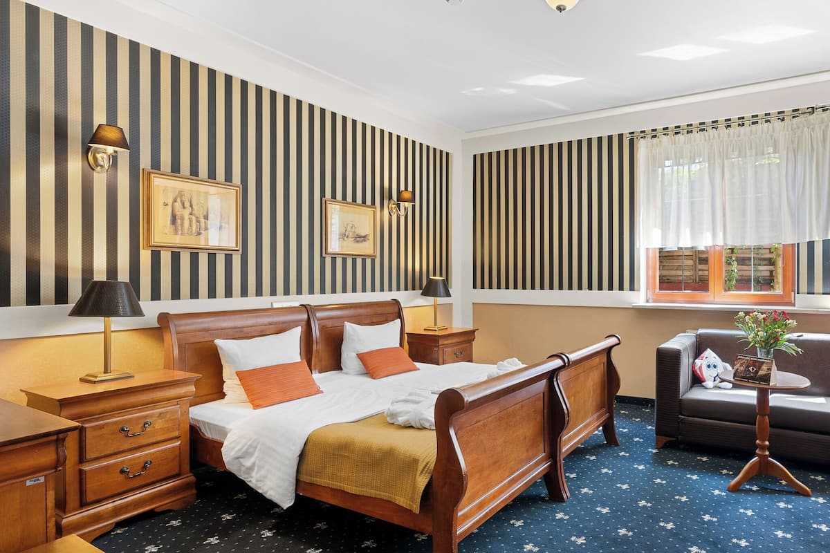 A hotel room with a wooden bed, striped wallpaper, and a window with curtains.