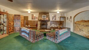 A cozy living room with a stone fireplace, patterned armchairs, and a collection of framed artwork. - Amargosa Opera House (Death Valley)