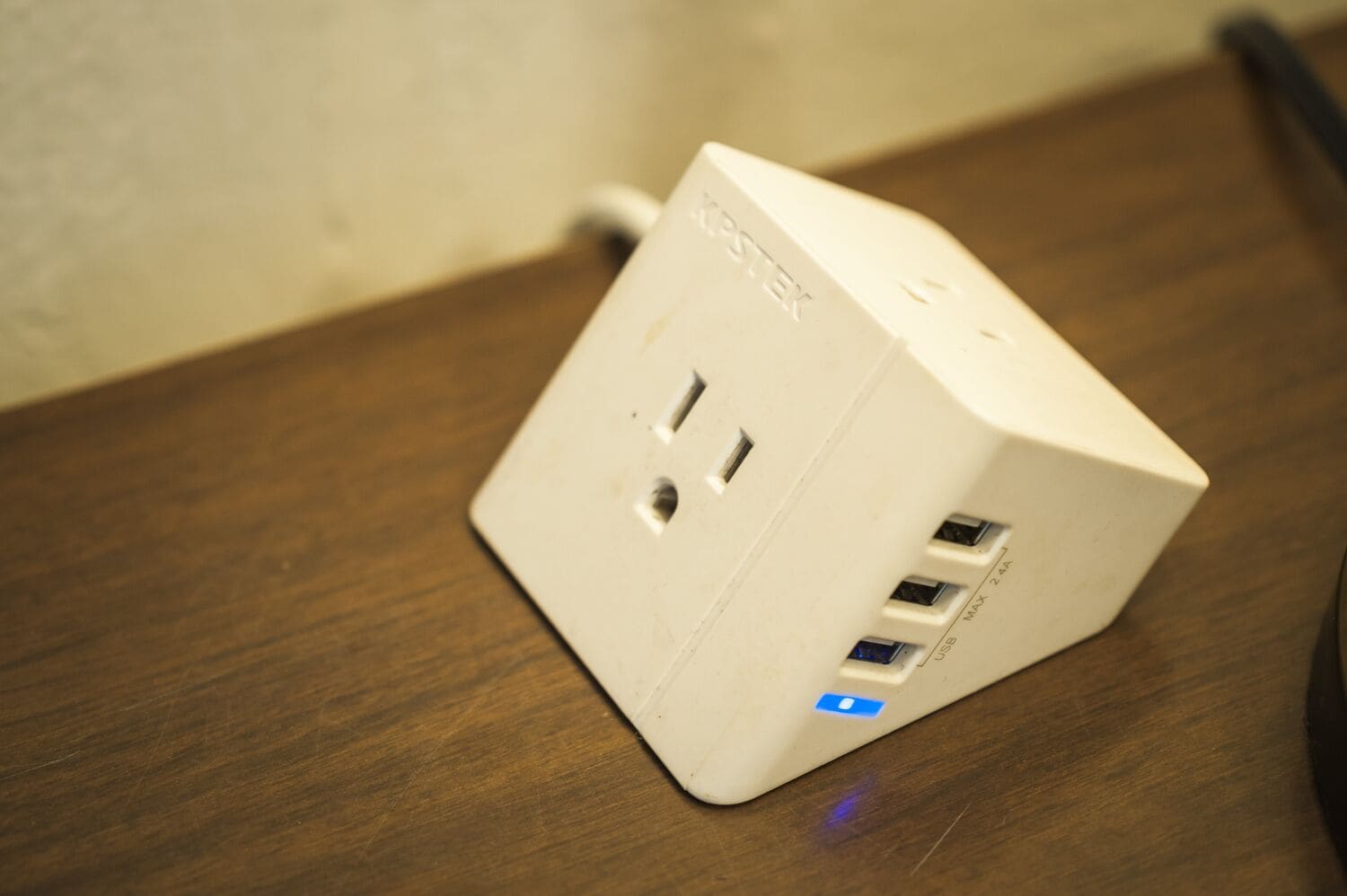Eine weiße Mehrfachsteckdose mit zwei USB-Anschlüssen und einer blauen Leuchtdiode auf einer Holtoberfläche.
