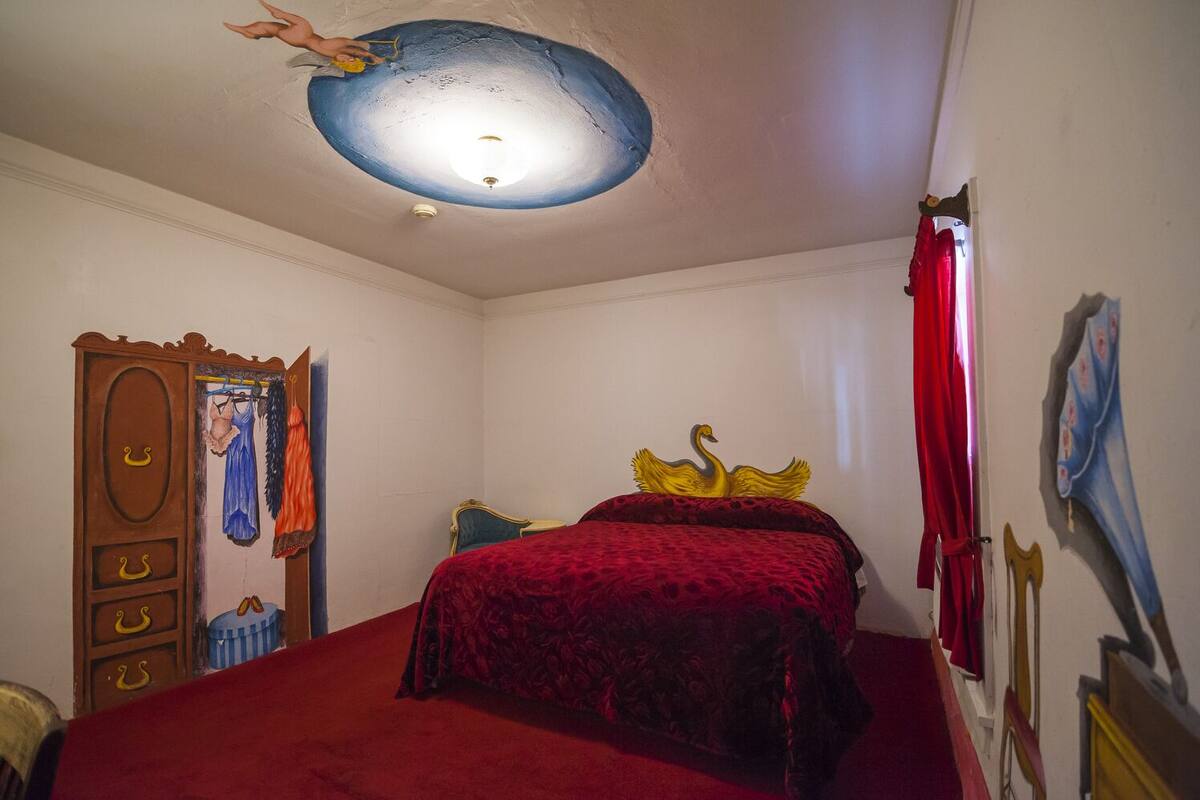 A bedroom with a bed, a wardrobe, a mirror, and a ceiling with a light fixture.