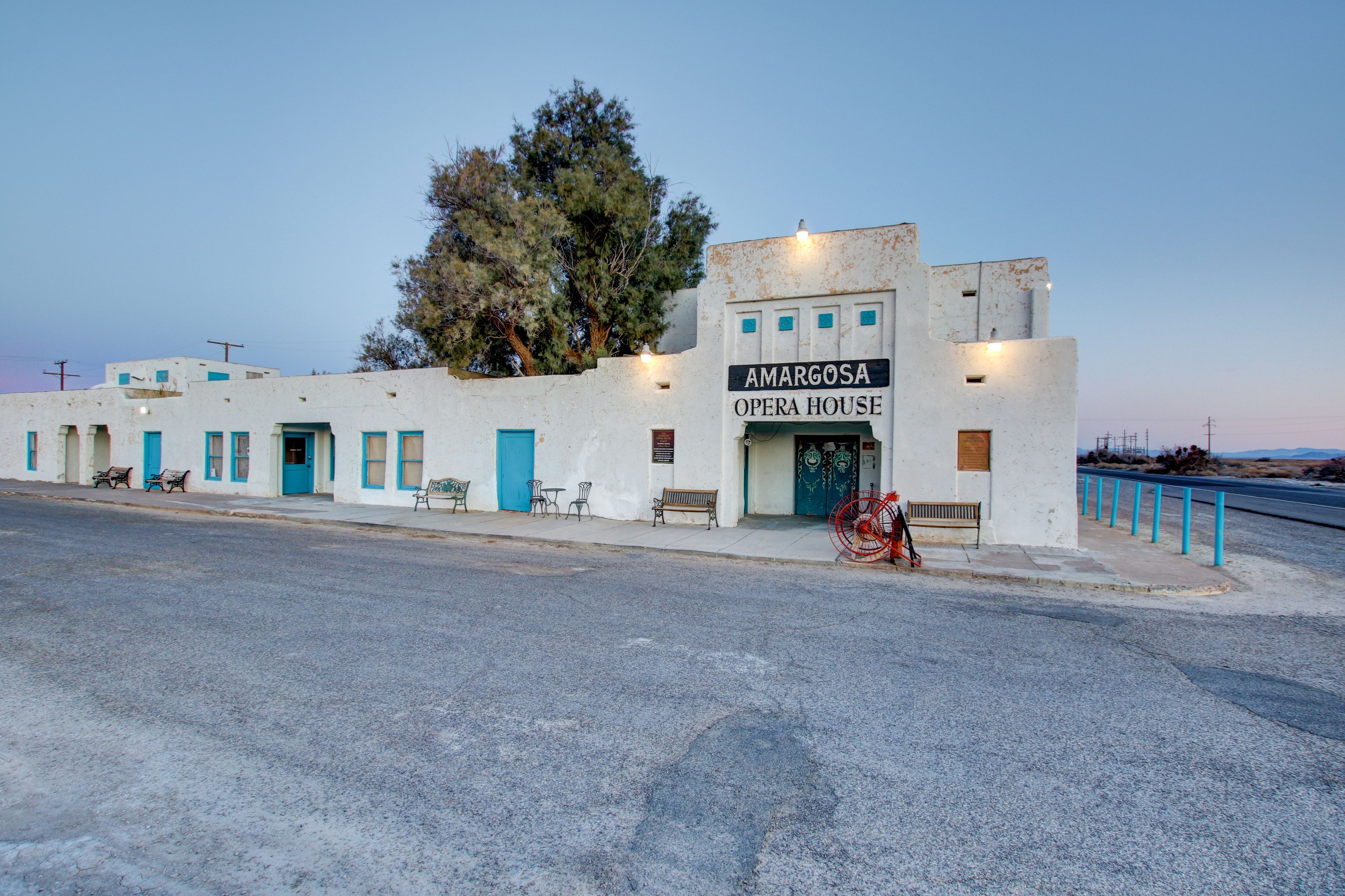 A building labeled "Amargosa Opera House" with a blue door, outdoor seating, and a red bicycle parked in front.
