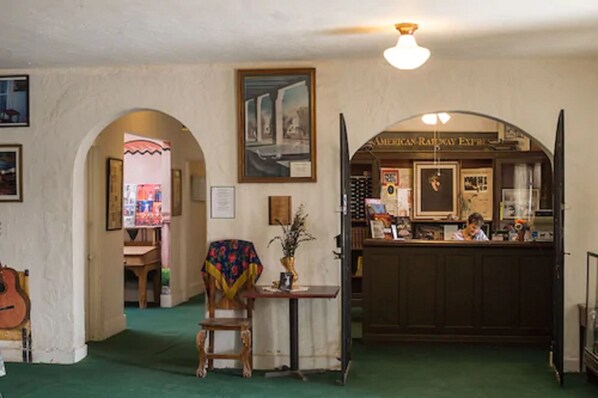 A room with a wooden chair, a table with a vase, a framed picture on the wall, and a counter with a sign reading "AMERICAN RAILWAY EXPRESS". - Amargosa Opera House (Death Valley)