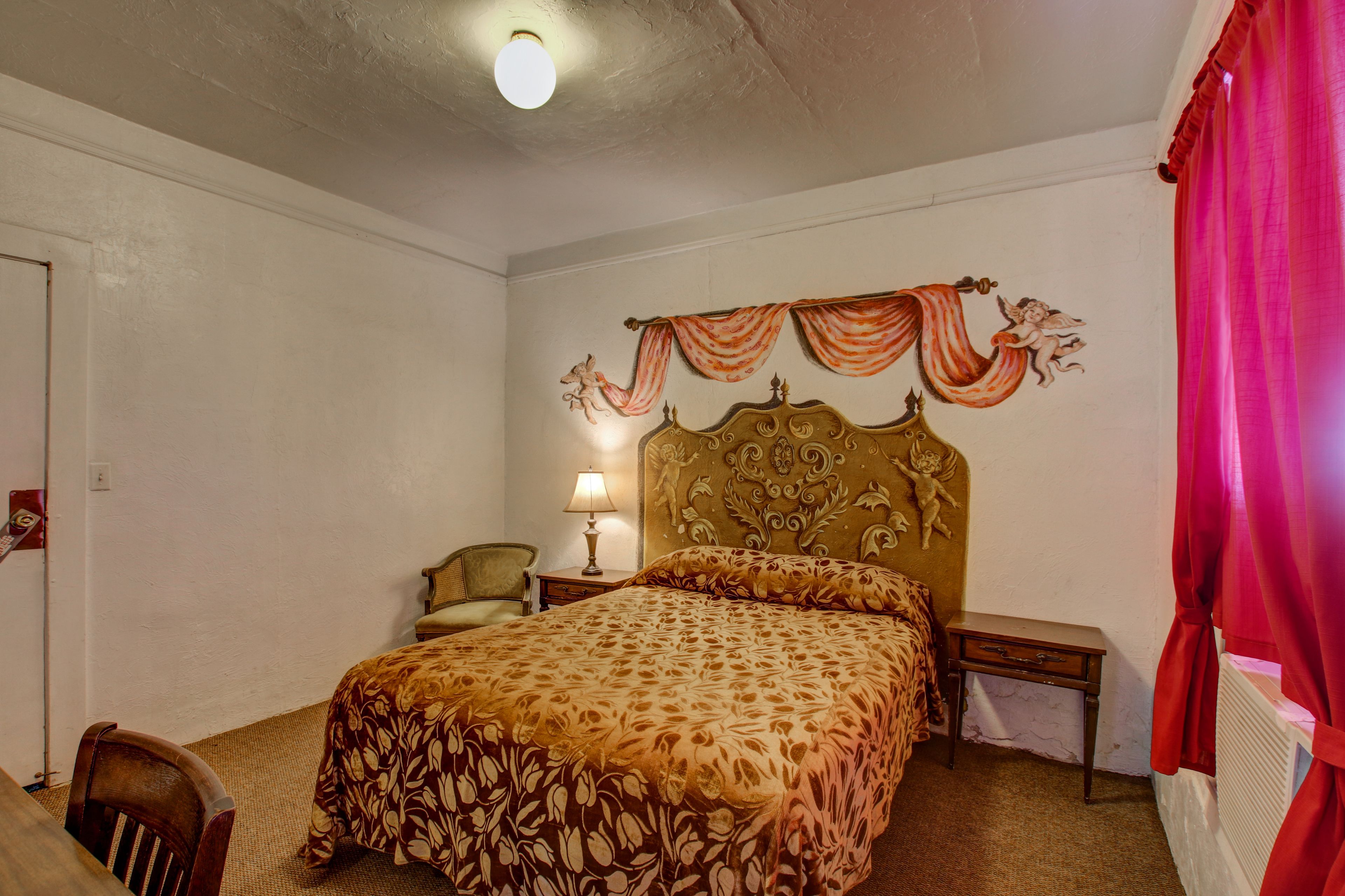 Un dormitorio con cama, una silla, una mesita de noche, una lámpara y un radiador.