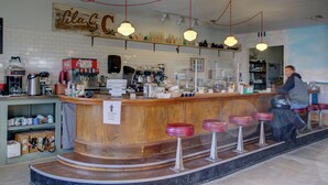A bar with a wooden counter, multiple stools, and a sign indicating payment options. - Amargosa Opera House (Death Valley)