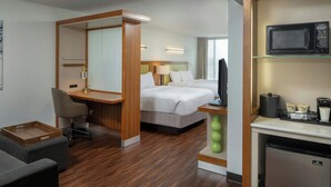 A hotel room with a wooden desk, two beds, a small kitchenette, and a seating area. - SpringHill Suites by Marriott Lake Charles (Lake Charles)