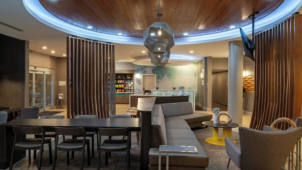 A modern interior with a round table, sofas, and a unique geometric light fixture. - SpringHill Suites by Marriott Lake Charles (Lake Charles)