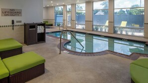 A pool area with a lifeguard sign, green cushioned seating, and a clear view of the outside. - SpringHill Suites by Marriott Lake Charles (Lake Charles)
