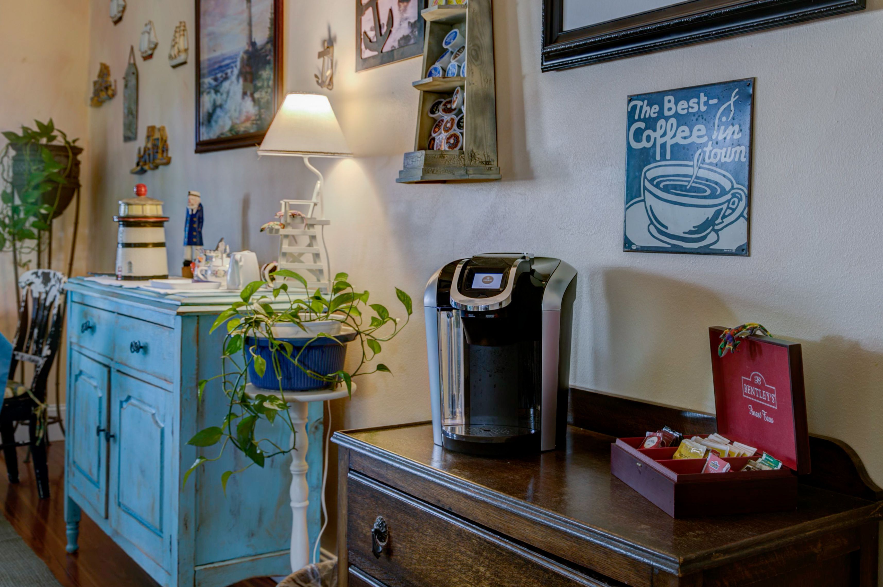 A coffee station with a coffee maker, a potted plant, and a coffee cup display on a counter.