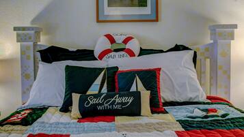 A bed with a quilt, pillows, and a framed picture on the wall.