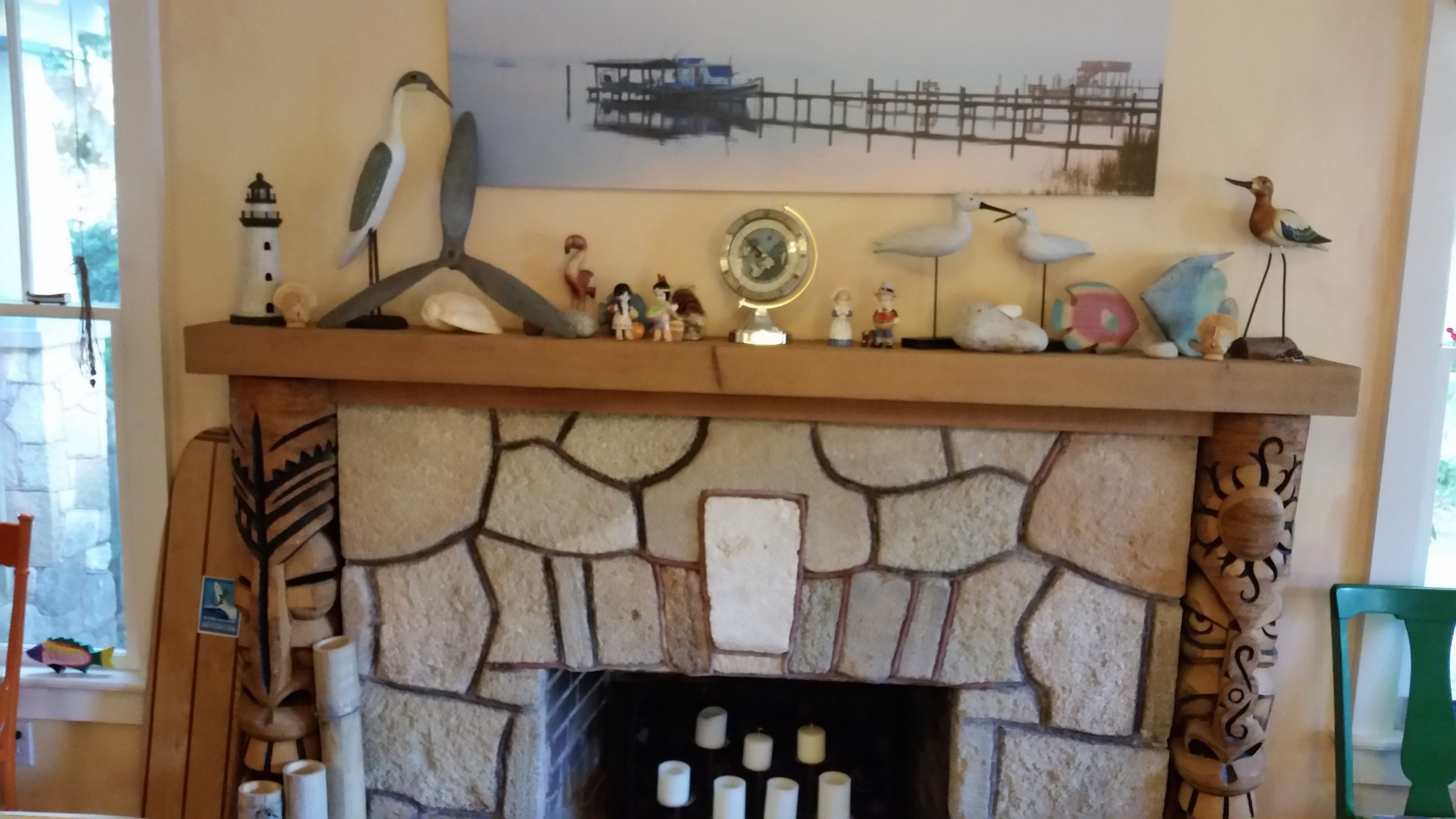 A fireplace with a stone mantle, decorative figurines, and a painting above it.
