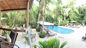 Un espacio al aire libre con piscina, sillones de descanso y mobiliario de madera.