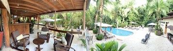 Un espacio al aire libre con piscina, sillones de descanso y mobiliario de madera.
