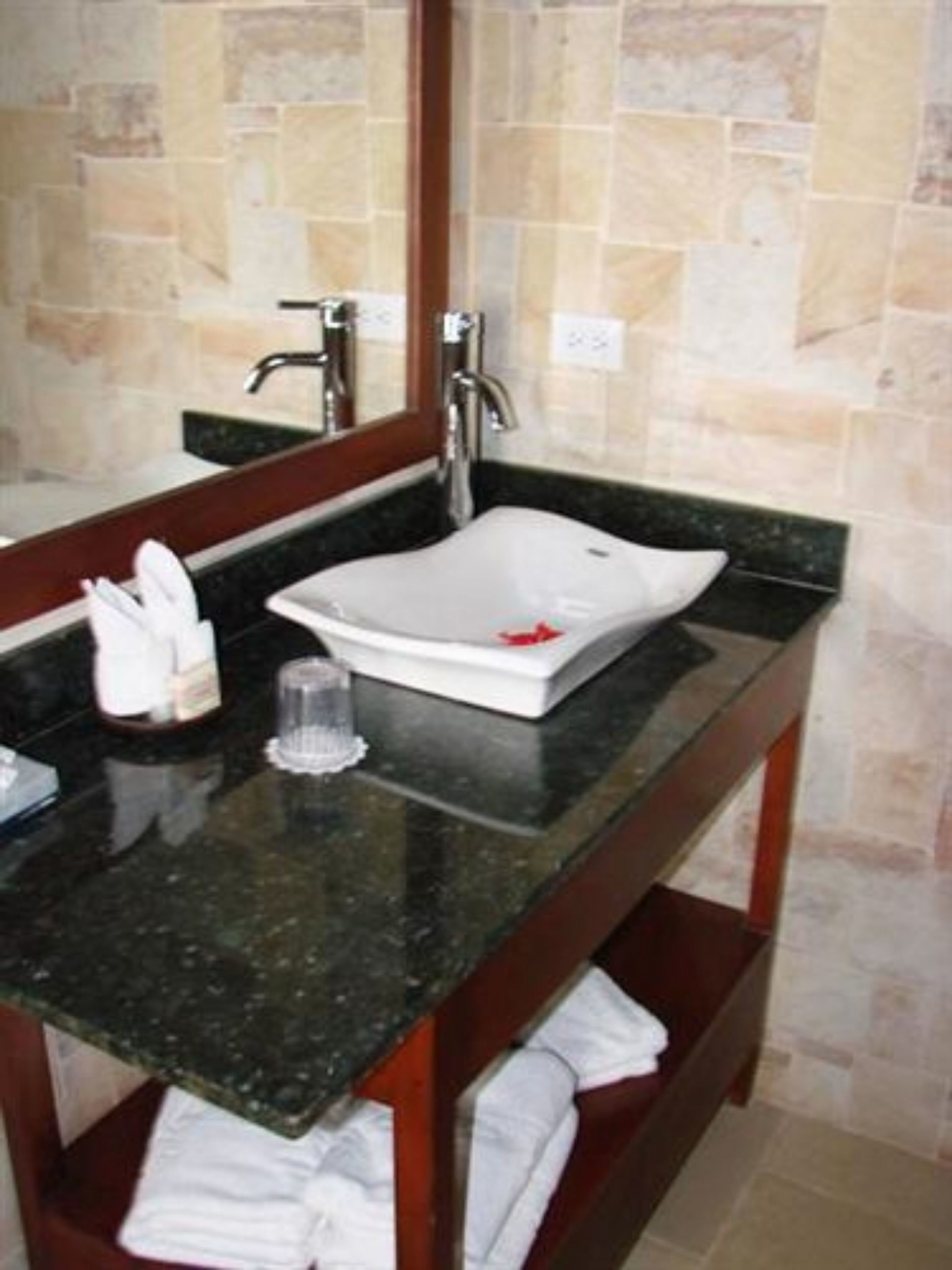 A bathroom with a rectangular white sink, a mirror above it, and a dark countertop.