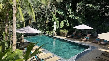 Una piscina al aire libre, sombrillas, tumbonas