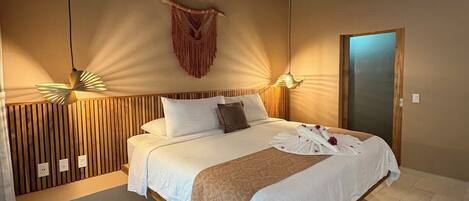 A bedroom with a wooden ceiling, a bed with white bedding, a wooden headboard, a wall-mounted macrame decoration, and a ceiling fan.