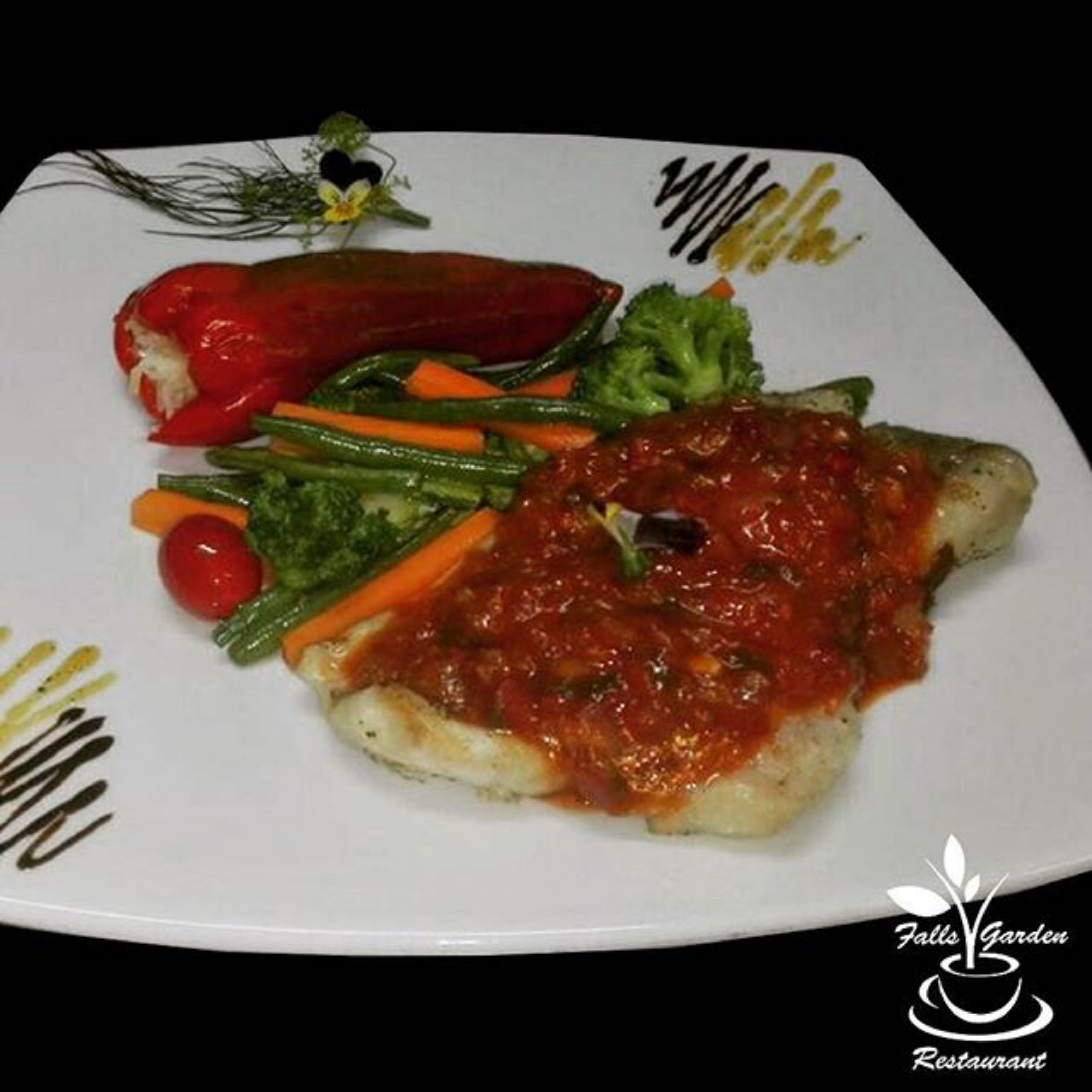 Plat de menjar amb un pebrot vermell, bròcoli, pastanagues i un tomàquet.
