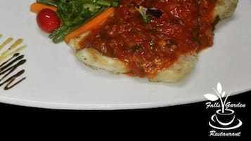 Plat de menjar amb un pebrot vermell, bròcoli, pastanagues i un tomàquet.