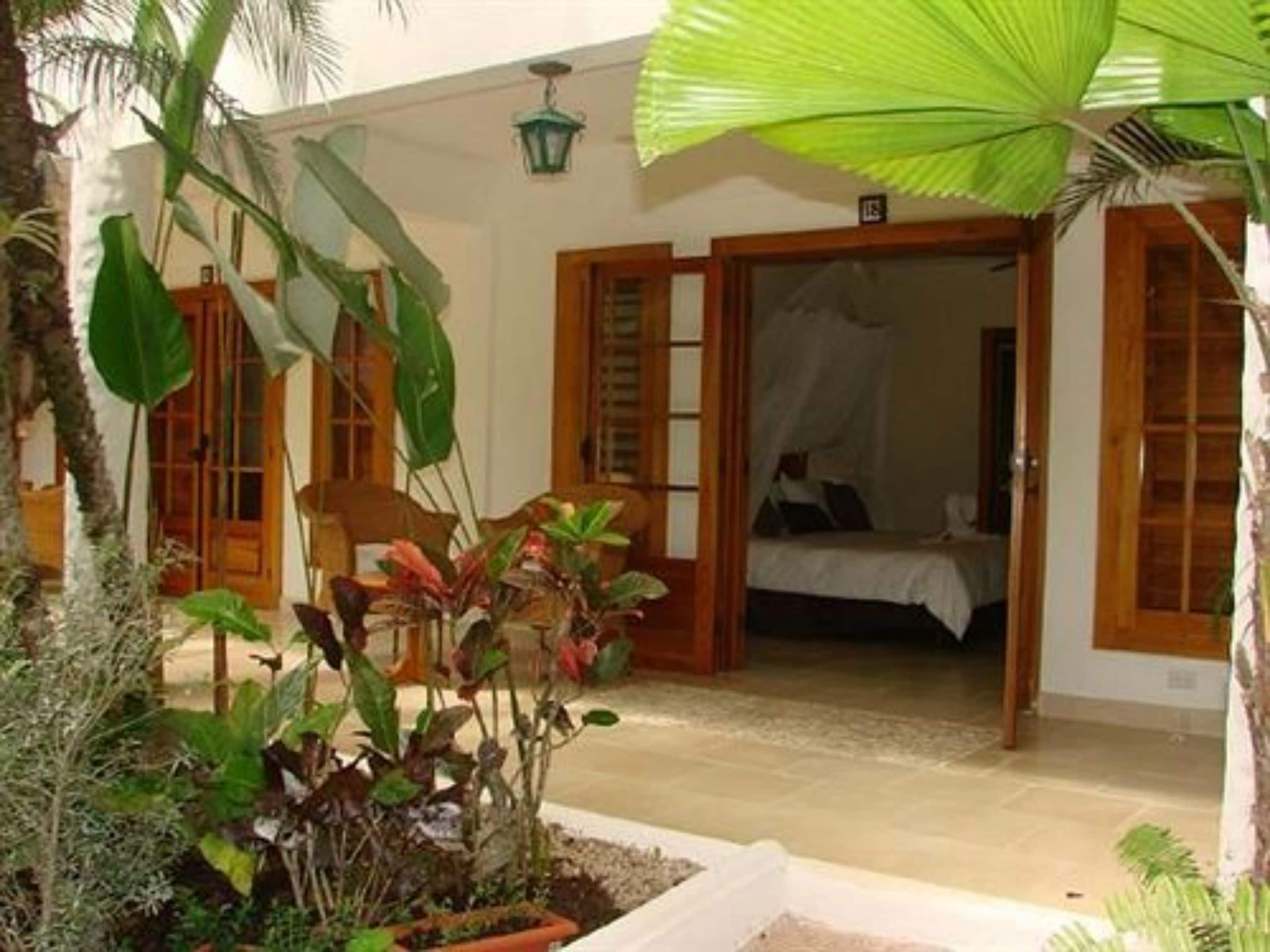 A room with a bed, a wooden door, and a large green umbrella.