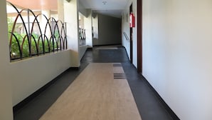 A corridor with a wooden floor, metal railings, and a fire extinguisher on the wall. - Century Plaza Hotel (Cebu City)