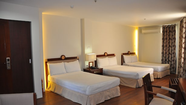 A hotel room with two single beds, a wooden chair, a small table, and a door. - Century Plaza Hotel (Cebu City)