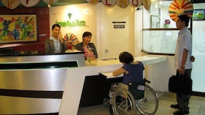 A reception desk with a sign that reads "PIT SENOR HOTEL". There is a wheelchair in front of the desk, and a man standing to the right. - Century Plaza Hotel (Cebu City)