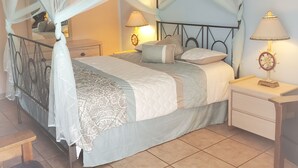 Un dormitorio con cama a dosel, lámparas de noche, una mesita de noche y un banco de madera.