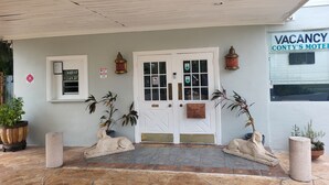 A motel entrance with a white door, a signboard, and potted plants.