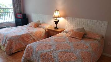 Una habitación con dos camas, cada una con ropa de cama estampada, una lámpara de noche y una mesita.