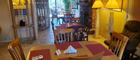 A dining area with a table set for two, chairs, and a lamp.