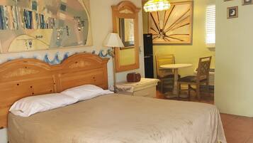 Een slaapkamer met een groot bed, een houten hoofdbord, een nachtkastje, een lamp, een stoel, een klein tafeltje en een wandklok.