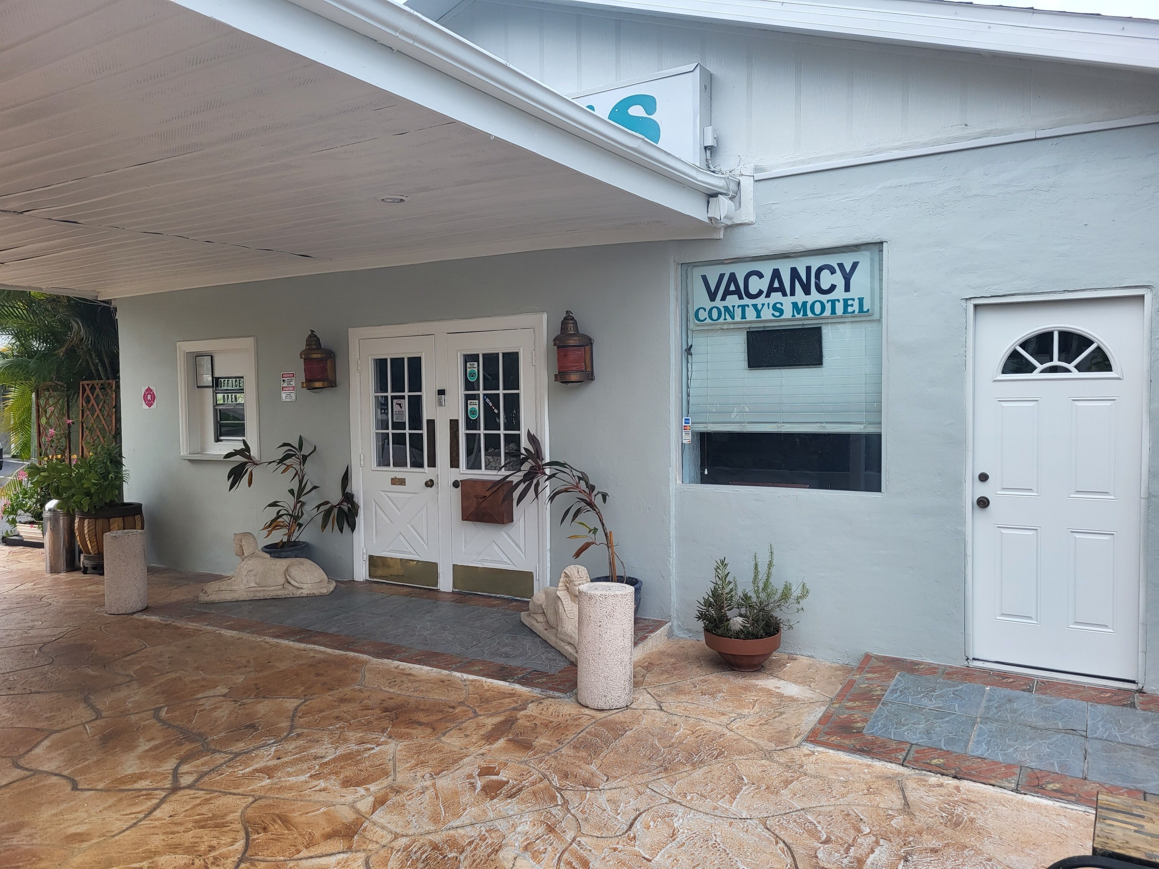 Ein Gebäude mit einem 'VACANCY'-Schild, einer weißen Tür und einem Schild mit der Aufschrift 'CONTY'S MOTEL'.