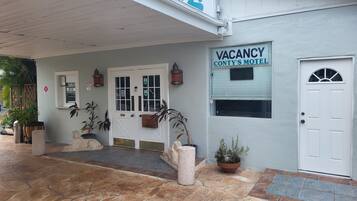 Ein Gebäude mit einem 'VACANCY'-Schild, einer weißen Tür und einem Schild mit der Aufschrift 'CONTY'S MOTEL'.