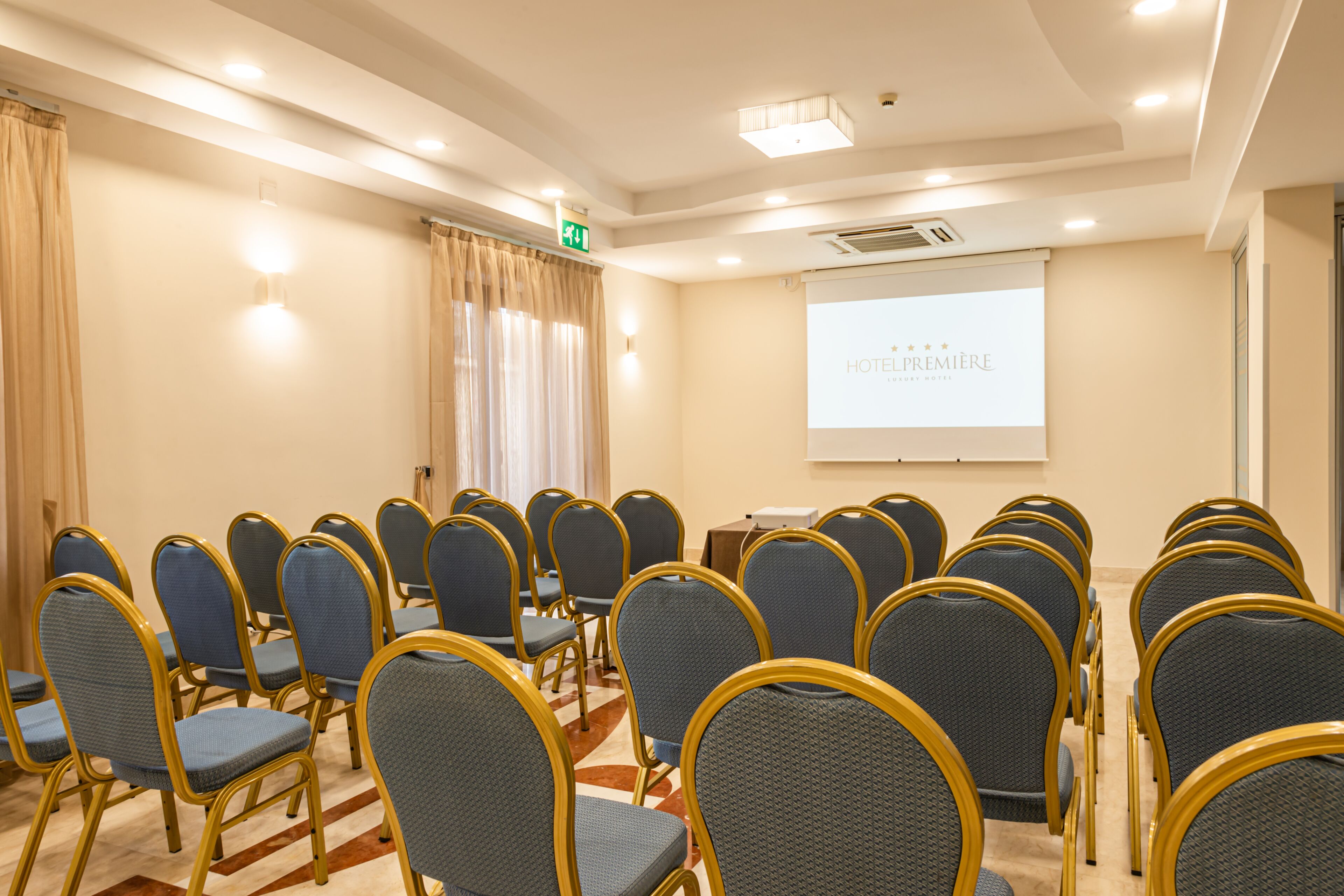 A conference room with rows of chairs, a projector screen, and a podium.